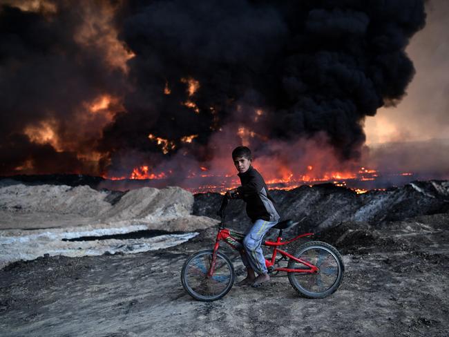 Getty Images Year in Focus 2016: A boy pauses on his bike as he passes an oil field that was set on fire by retreating ISIS fighters ahead of the Mosul offensive, on October 21, 2016 in Qayyarah, Iraq. Several hundred Iraqi families have been made to leave their homes for Mosul by Islamic State fighters as the UN warns they could be used as human shields. ISIS have attacked Kirkuk today as Kurdish and Iraqi forces, backed by a coalition including Britain and the U.S.A continue their offensive to retake Iraq’s second largest city of Mosul. Photo by Carl Court/Getty Images