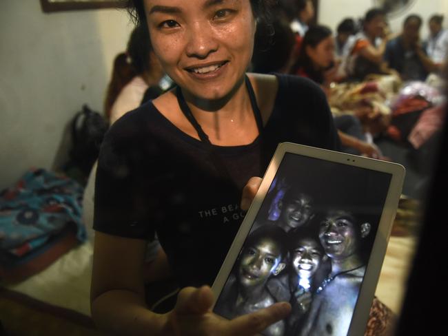 A family member shows a picture of four of the twelve missing boys. Picture: AFP