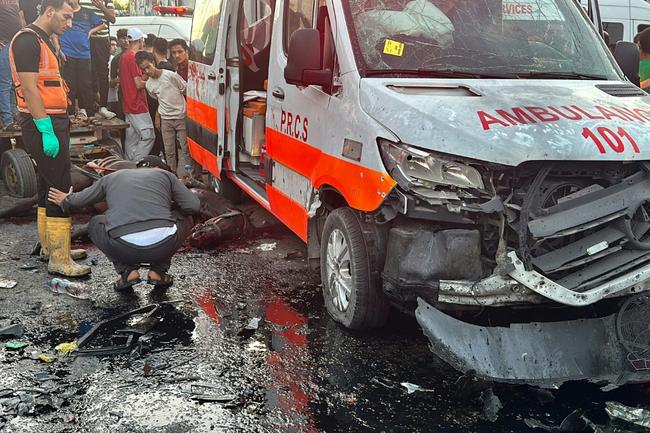 Onlookers outside Gaza's largest hospital Al-Shifa gather around a Red Crescent ambulance damaged in a deadly Israeli strike