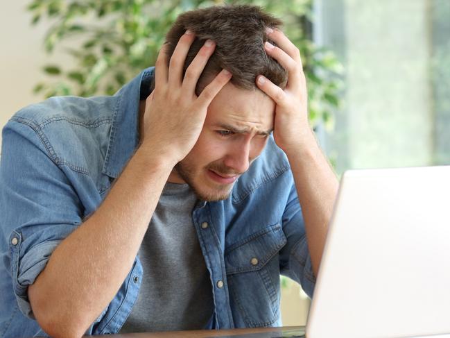 A stressed man at his computer after just realising he has been scammed. Picture: iStock.