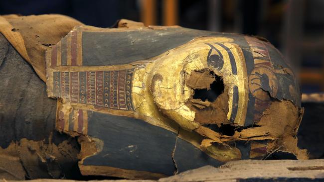 In this photo taken Friday, Dec. 5, 2014, in Chicago, the mummified body of Minirdis, a 14-year-old Egyptian boy and his burial mask lie in his opened coffin after J.P. Brown and his team of curators at the Field Museum opened the coffin for the first time. Brown and his team will begin conservation work on the 2,500-year-old boy before it becomes part of a traveling exhibition. Brown says they have to fix his burial mask, shroud, reconnect his detached feet, and do work to shore up the coffin and mummy so they can withstand travel. (AP Photo/Charles Rex Arbogast)