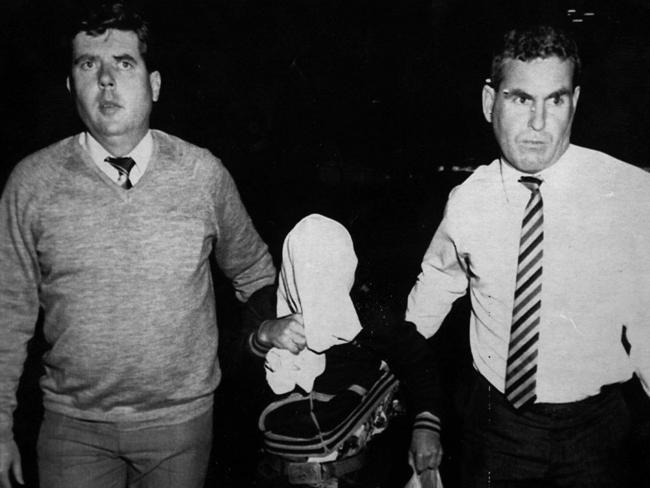 Stephen “Shorty” Jamieson is escorted by NSW police from Southport police station on his way to Brisbane Airport in 1988.