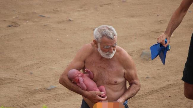 A man believed to be a doctor carries the child after the birth. Picture: Hadia Hosny El Said/CEN/australscope