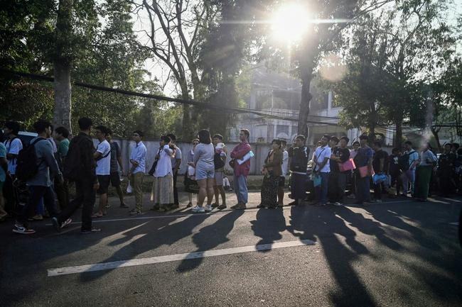 People stand in line to get visas at the Thai embassy in Yangon after Myanmar's military government said it would impose military service