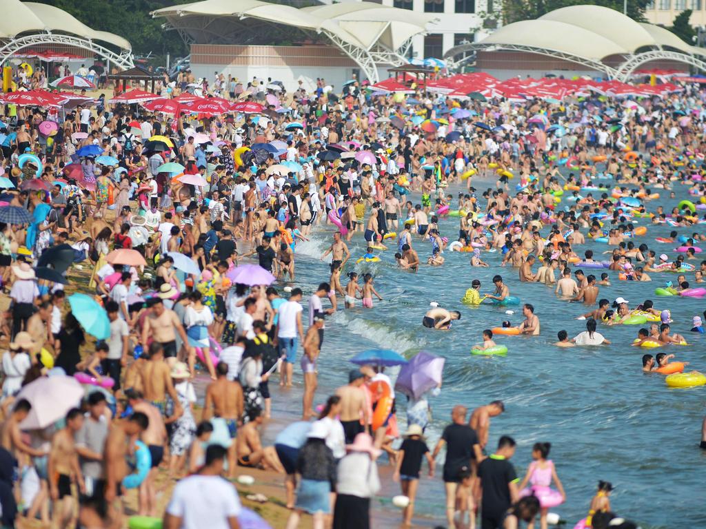 This photo taken on July 14, 2018 shows people cooling off on a beach amid high temperatures in Qingdao, east China's Shandong province. / AFP PHOTO / - / China OUT