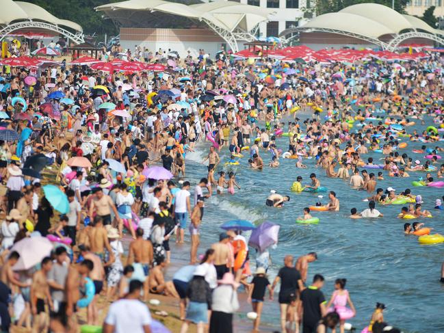 This photo taken on July 14, 2018 shows people cooling off on a beach amid high temperatures in Qingdao, east China's Shandong province. / AFP PHOTO / - / China OUT