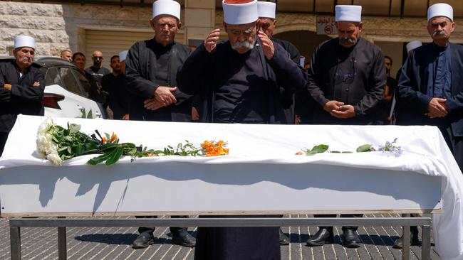 Druze elders and mourners pray by the coffin of Guevara Ibrahim, 11, killed in the rocket attack. Picture: AFP.