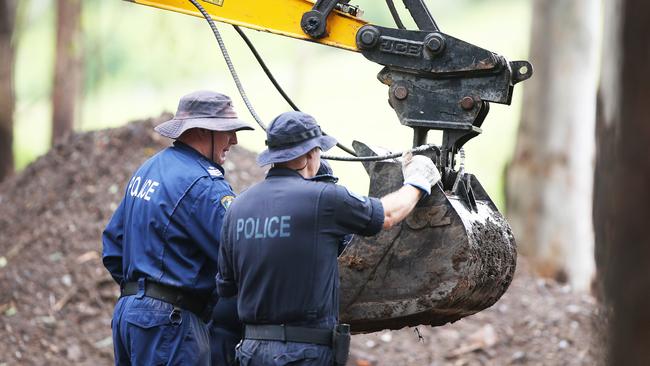 Police officers inspect items at the search site today. Picture: Peter Lorimer.