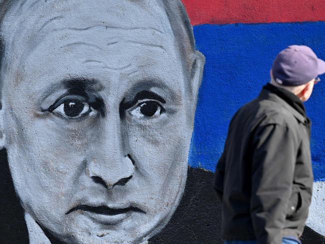 A man walks past a mural depicting Russian President Vladimir Putin, with the Russian flag, in Belgrade on March 5, 2022. (Photo by Andrej ISAKOVIC / AFP)