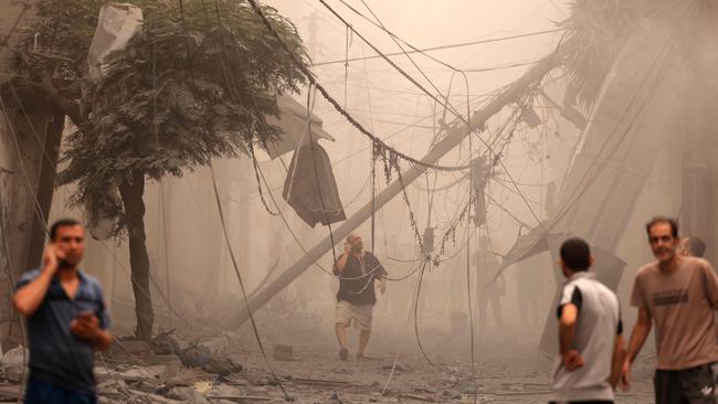 Palestinians inspect the destruction in a neighbourhood heavily damaged by Israeli air strikes on Gaza City's Shati refugee camp. Picture: AFP