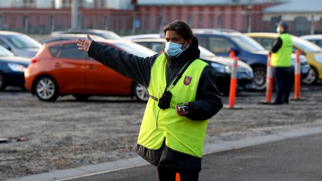 A worker directing people at a Covid testing station at the Melbourne Showgrounds. Picture: Andrew Henshaw