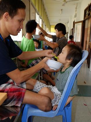 Truong Minh Hiep, aged 16, born with physical deformities feeds breakfast to Tran Thi Ngoc Nhu, aged 8, with Down ’s syndrome. Photo: Ash Anand / NEWSMODO