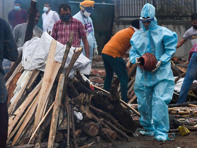 A man wearing a personal protective equipment suit perform the last rites before the cremation of his relative who died due to the COVID-19 at a cremation ground in New Delhi. Picture: AFP