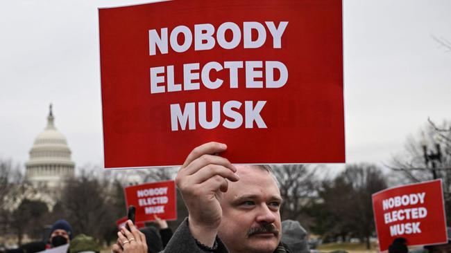 People hold up signs as they protest against US President Donald Trump and Elon Musk's "Department of Government Efficiency" (DOGE) outside of the US Department of Labor near the US Capitol in Washington, DC, February 5, 2025. (Photo by Drew ANGERER / AFP)