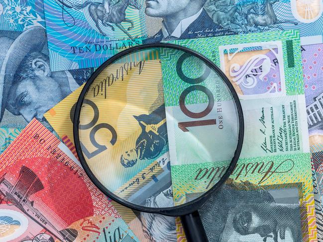 Magnifying glass on australian dollar banknote as background; Australian money generic banking