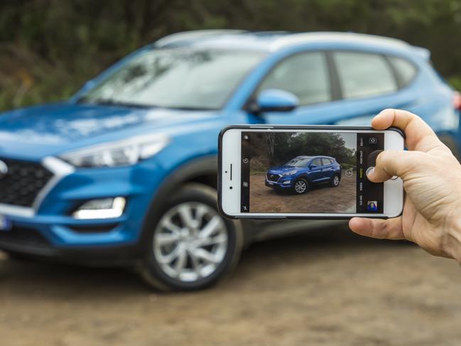 Generic photo of person taking photo of their car