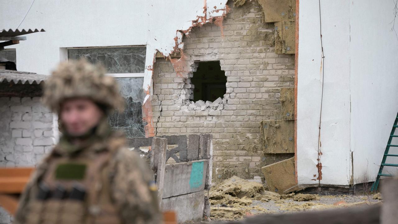 A Ukrainian soldier stands next to a damaged wall after the reported shelling of a kindergarten in Luhansk on February 17, 2022. Picture: AFP