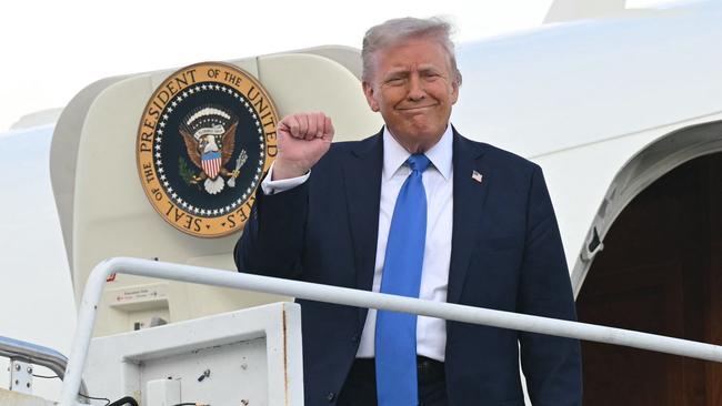 US President Donald Trump raises a fist as he steps off Air Force One upon arrival at Tuscaloosa National Airport in Tuscaloosa, Alabama.