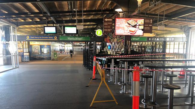 The scene at Manly Wharf at 11.24am on Easter Sunday. One lonely passenger heads for the ferry. Tables and chairs are taped off to prevent people sitting. Picture: Julie Cross.