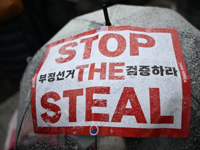 Snow is seen on a demonstrator's umbrella with a placard that reads 