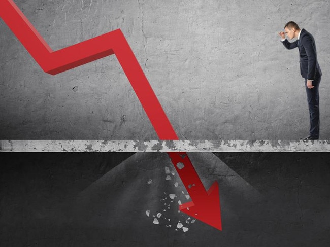 Businessman looking down at the falling red arrow destroying a concrete barrier. Collapse and drop. Fall and depreciation. Regression and deterioration. Crisis.