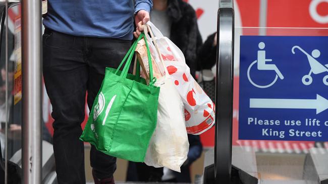 A shopper carries his own bags, as well as a reusable plastic bag, out of a Coles supermarket in Sydney. Pic: AAP