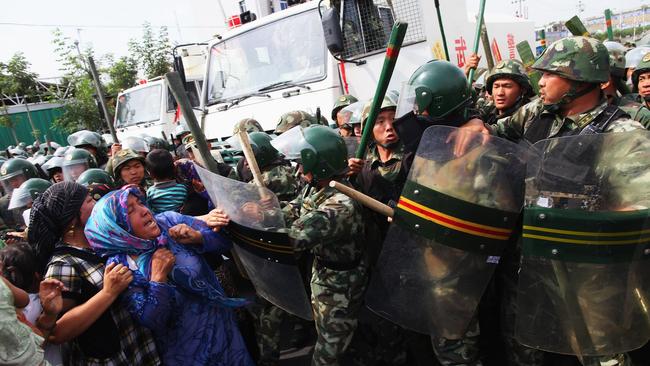 Uighur women are pushed back by policemen on a street in Urumqi, the capital of Xinjiang, China. Beijing claims terrorist groups are stoking unrest in the region. Picture: Getty