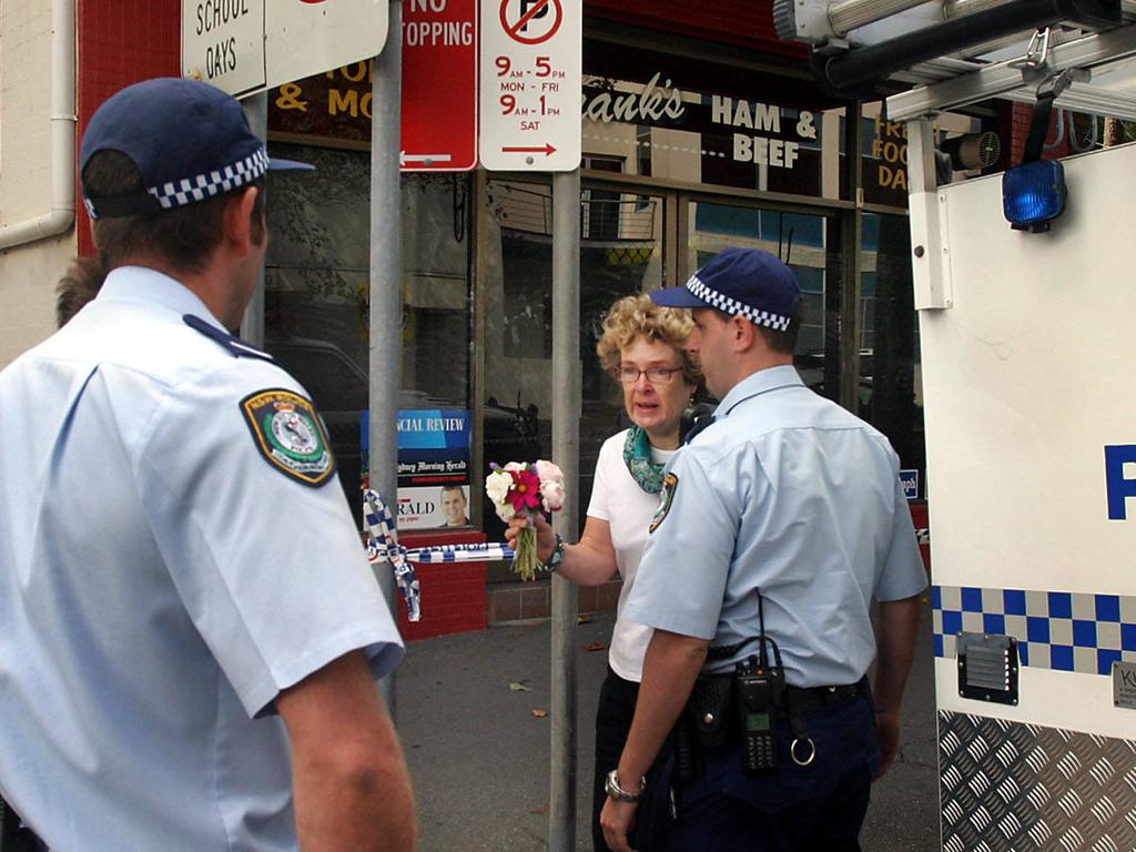 A distraught woman arrives with a bouquet of flowers to the scene of the murder of store owner Frank Newbery, 87, in Union St, Newcastle.