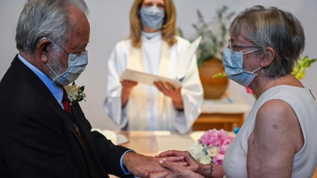 Linda Delk, right, puts a ring on the finger of Ardell Hoveskeland as Pastor Sarah Scherschligt looks on during their socially distanced wedding in Alexandria, Virginia. Picture: AFP