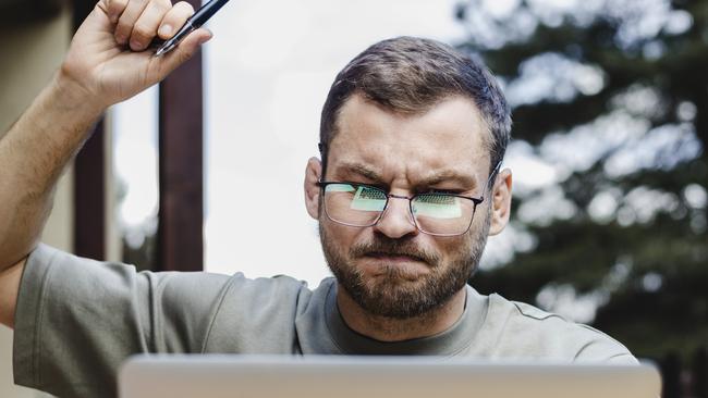 Adult man  in glasses working on laptop outdoors.; angry investor generic money investing