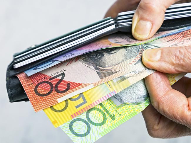 Close-up, senior female hands taking Australian banknotes (cash, currency) from purse containing many credit cards.  Horizontal, studio, copy space. Money generic