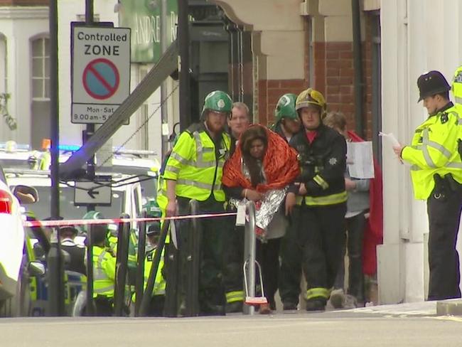 A woman with blankets wrapped around her is escorted by emergency services near the scene of an explosion in London. Picture: AP