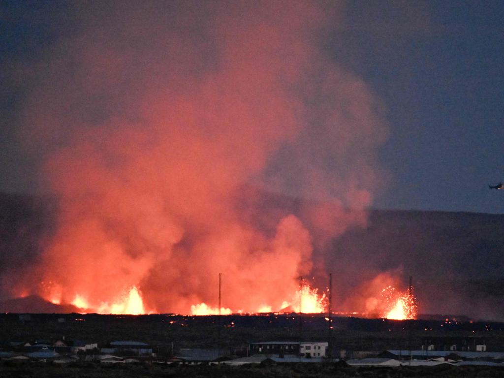 A helicopter flies near lava explosions and smoke near residential buildings after a volcanic eruption on January 14. Picture: Halldor Kolbeins/AFP