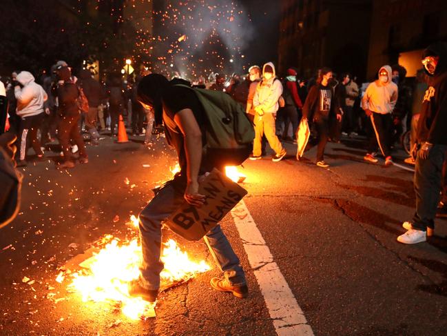 A demonstrator tried to extinguish a trash fire during a protest in Oakland, California. Picture: Getty