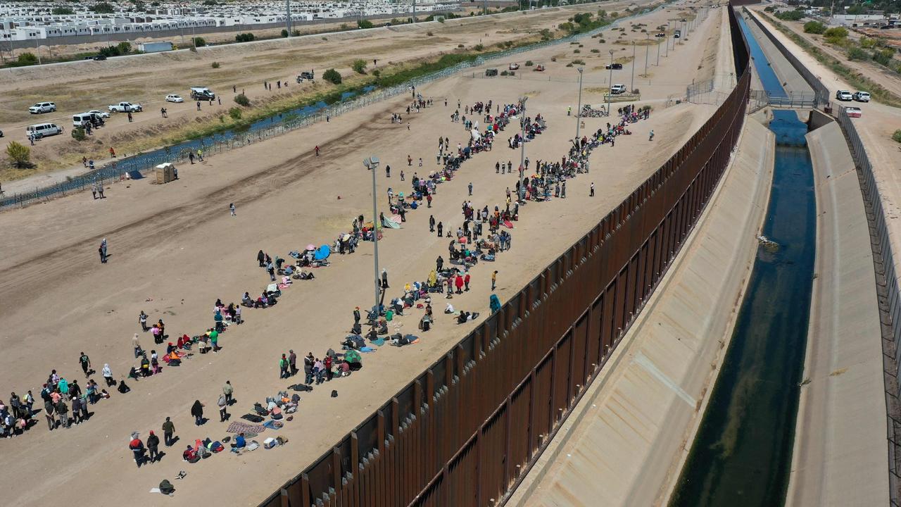 Migrants waiting along the border wall to surrender to US Customs and Border Protection after crossing the Rio Grande River into the US, on the US-Mexico border in El Paso, Texas. Picture: Patrick T. Fallon / AFP