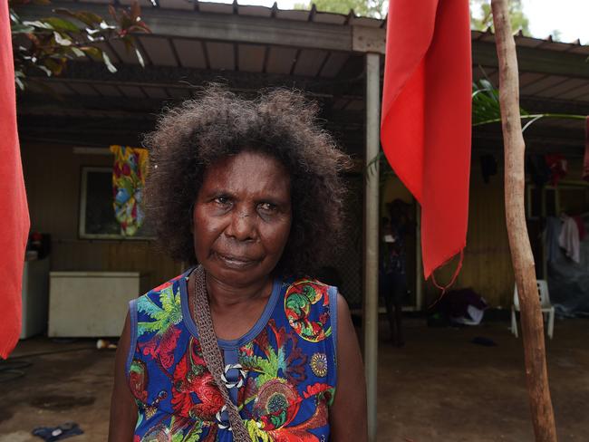 Susan Gurruwiwi stands between the funeral flags hung for her deceased husband at her home in Gunyangara. Picture: Keri Megelus