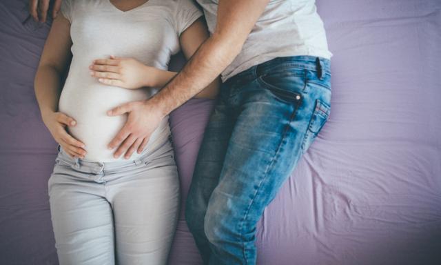 Father to be cuddle his pregnant womanin bed
