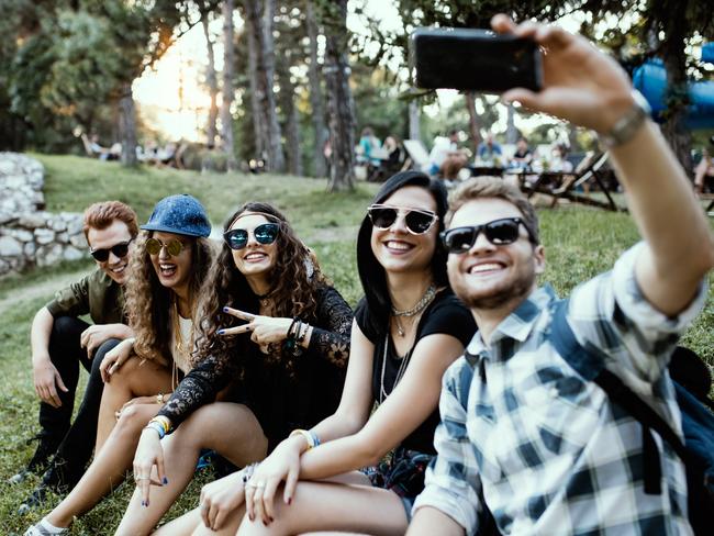 Friends sitting in the grass, having a laugh and taking selfie