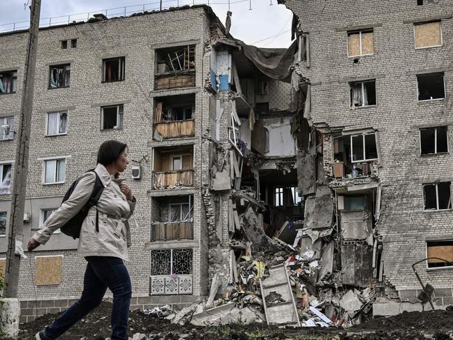 TOPSHOT - A woman walks by a destroyed apartment building in Bakhmut in the eastern Ukranian region of Donbass on May 22, 2022, amid Russian invasion of Ukraine. (Photo by ARIS MESSINIS / AFP)