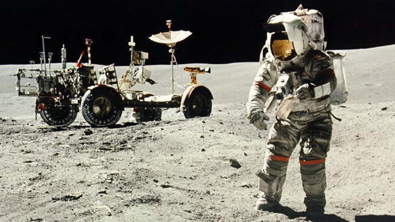 Apollo 16 astronaut Charles Duke in front of the rover vehicle on the surface of the moon.