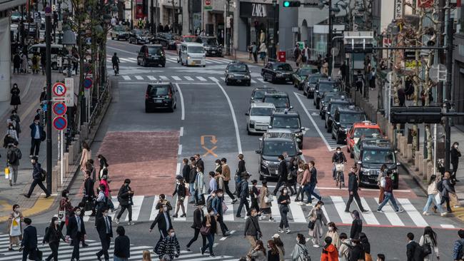 People, some wearing face masks, cross a road in Tokyo. Picture: Getty Images