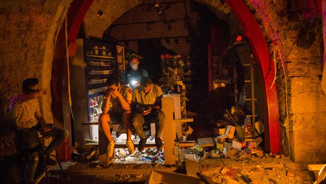 A group of men sit near the entrance of a damaged shop in Beirut, Lebanon. Picture: Getty Images