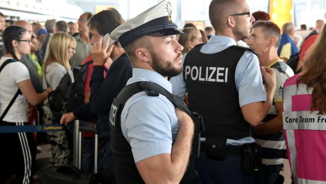 Police officers and travellers wait in the departure area of the airport in Frankfurt. Picture: AFP