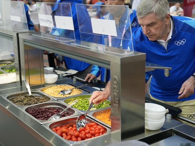 PARIS, FRANCE - JULY 22:  IOC President Thomas Bach tries food from a salad bar while touring the Olympic Village ahead of the start of the Paris 2024 Olympic Games on July 22, 2024 in Paris, France. (Photo by David Goldman - Pool/Getty Images)