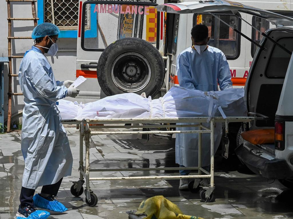 Ambulance staff take out the body of a person who died from coronavirus. The death industry is overwhelmed and some are starting their own businesses to cope. Picture: AFP