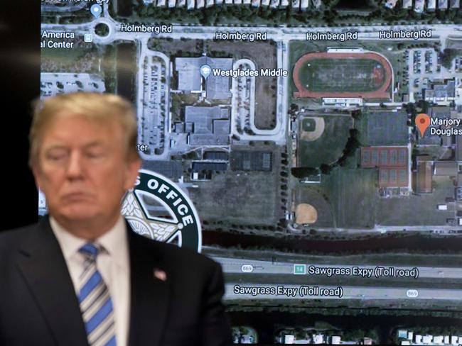 A photograph of Marjory Stoneman Douglas High School is visible behind President Donald Trump as he meets with law enforcement officers at Broward County Sheriff's Office. Picture: AP