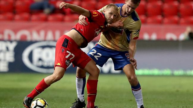 Adelaide United’s Dzengis Cavusevic is tackled by Newcastle Jets Lachlan Jackson at Coopers Stadium in Adelaide. Picture: James Elsby/AAP