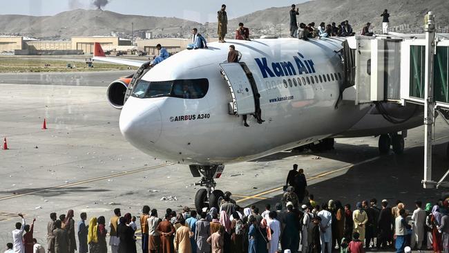 Afghans climb atop a plane as they wait at the Kabul airport on Monday. Picture: AFP