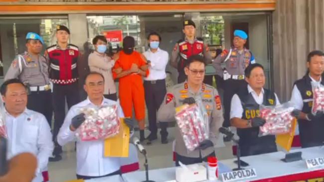 Lamar Ahchee is pictured in an orange prison jumpsuit before a crowd of locals, behind the cocaine he allegedly tried to smuggle into Indonesia.
