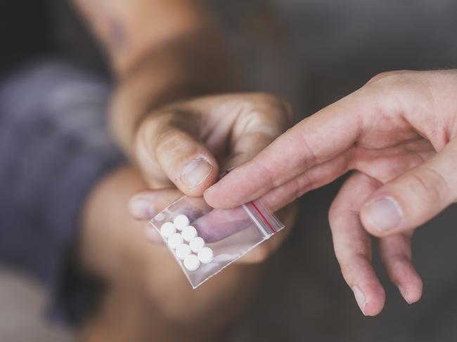 Drug dealer selling ecstasy pills to a drug addict drug dealer istock